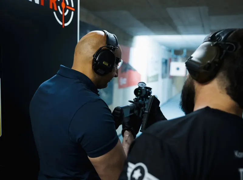 Trainer erklärt einem Teilnehmer die Waffe